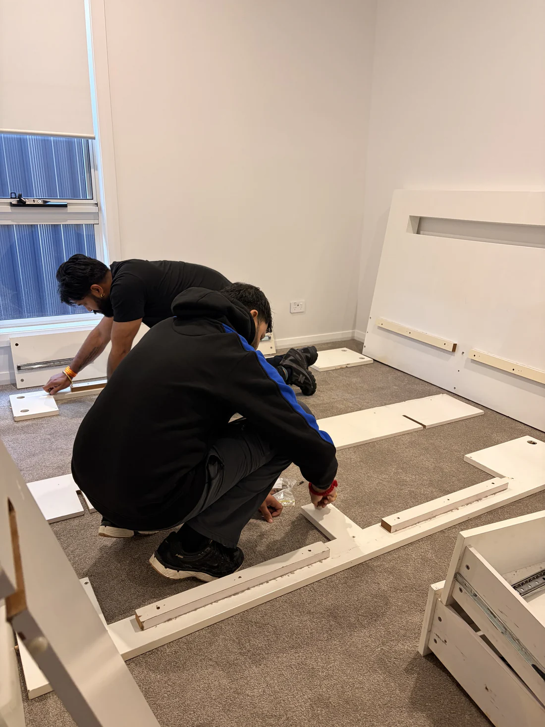 Two of the crew reassembling a bed frame in the new bedroom