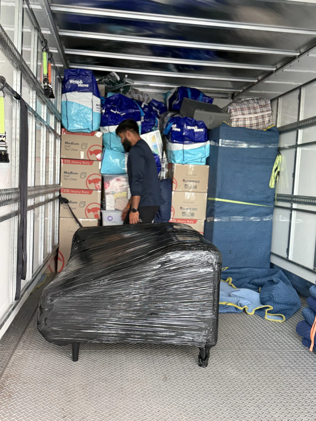 Blanket-wrapped furniture and labelled cartons strapped inside the truck